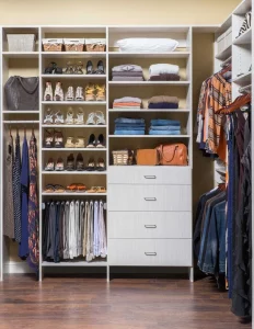 Well organized closet with folded sweaters and shoe racks.