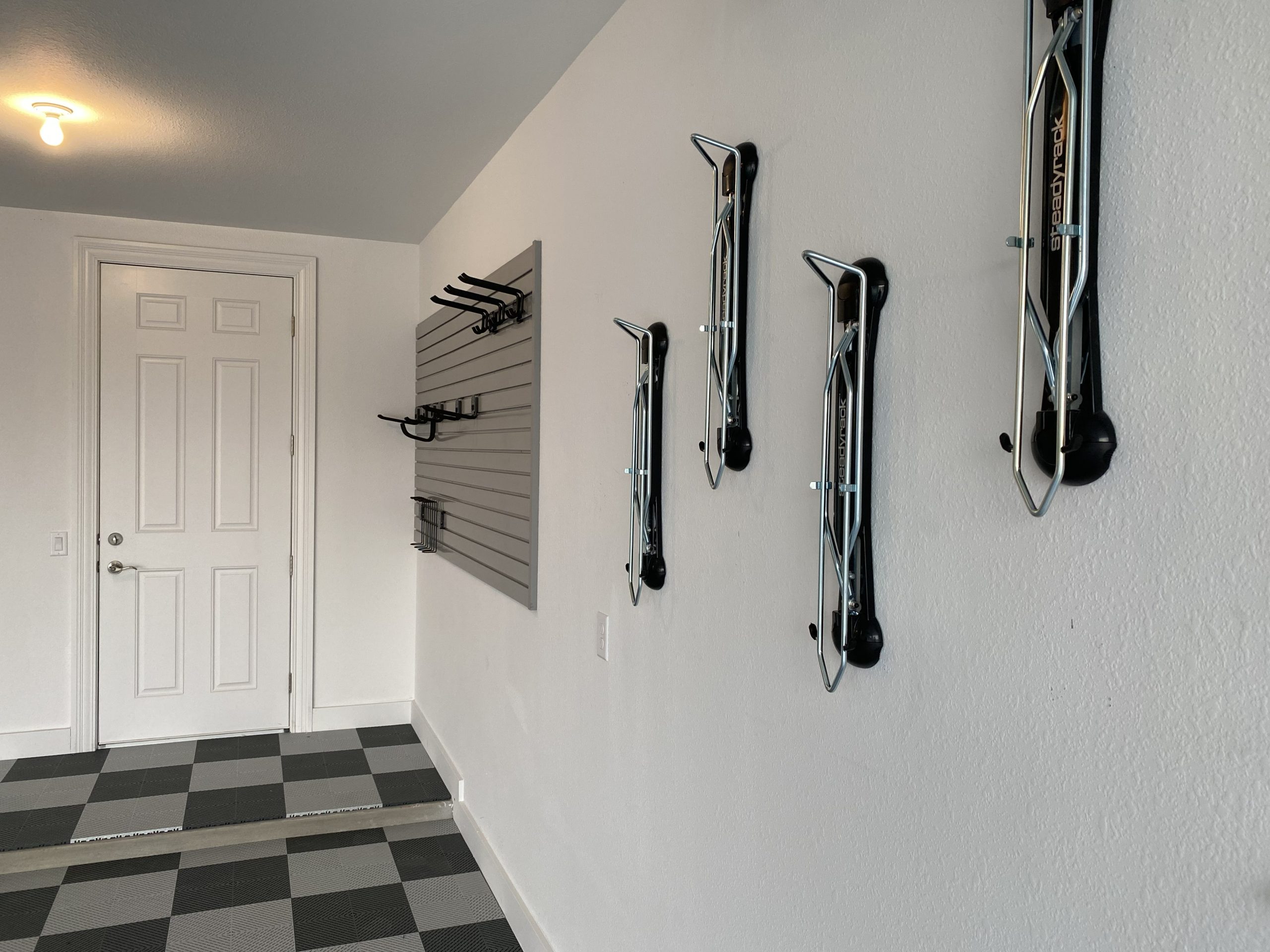 Organized garage with hooks and shelves on the wall for storage. 