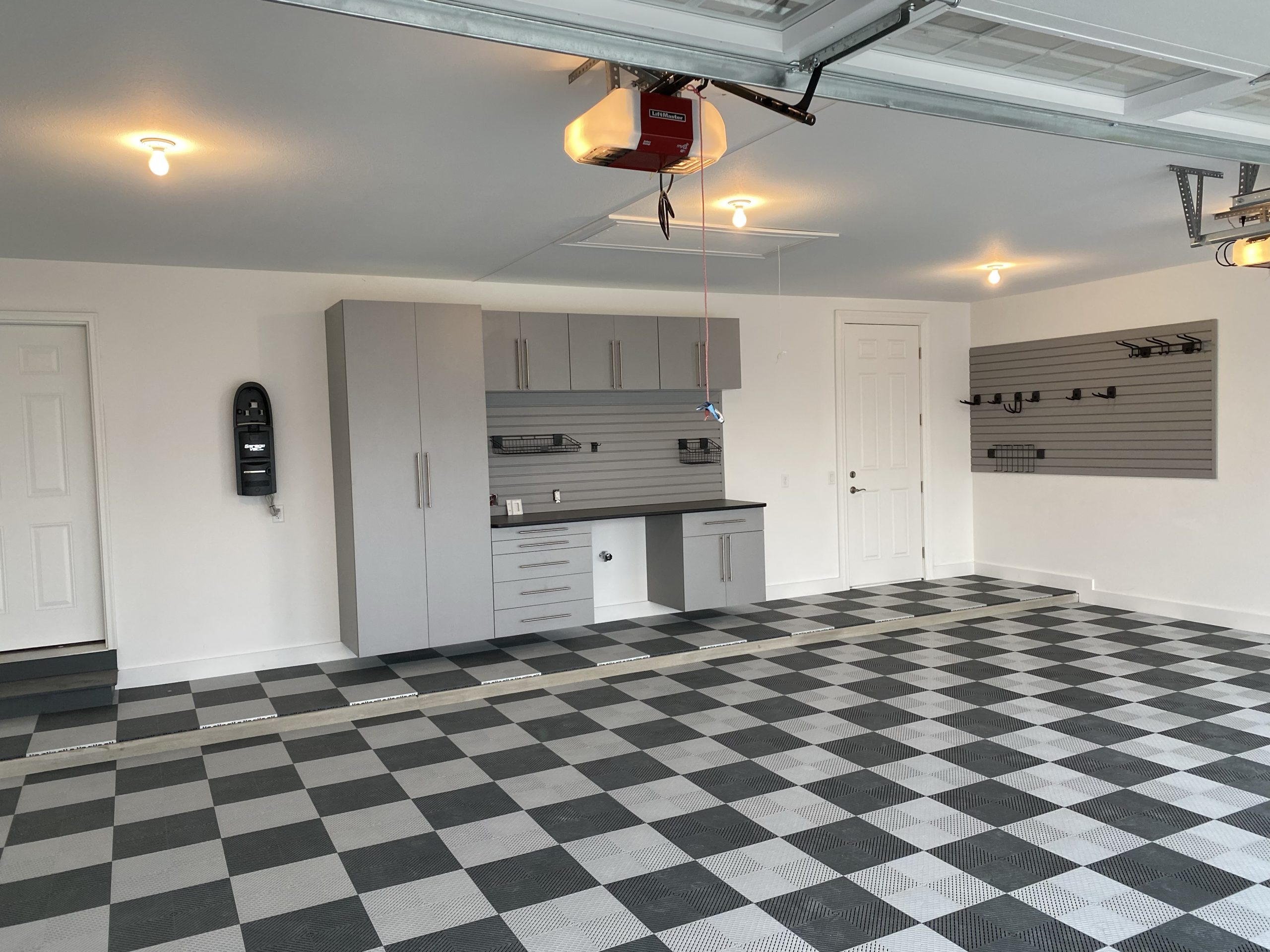 Organized garage with a checkered floor and a custom built organizational system.