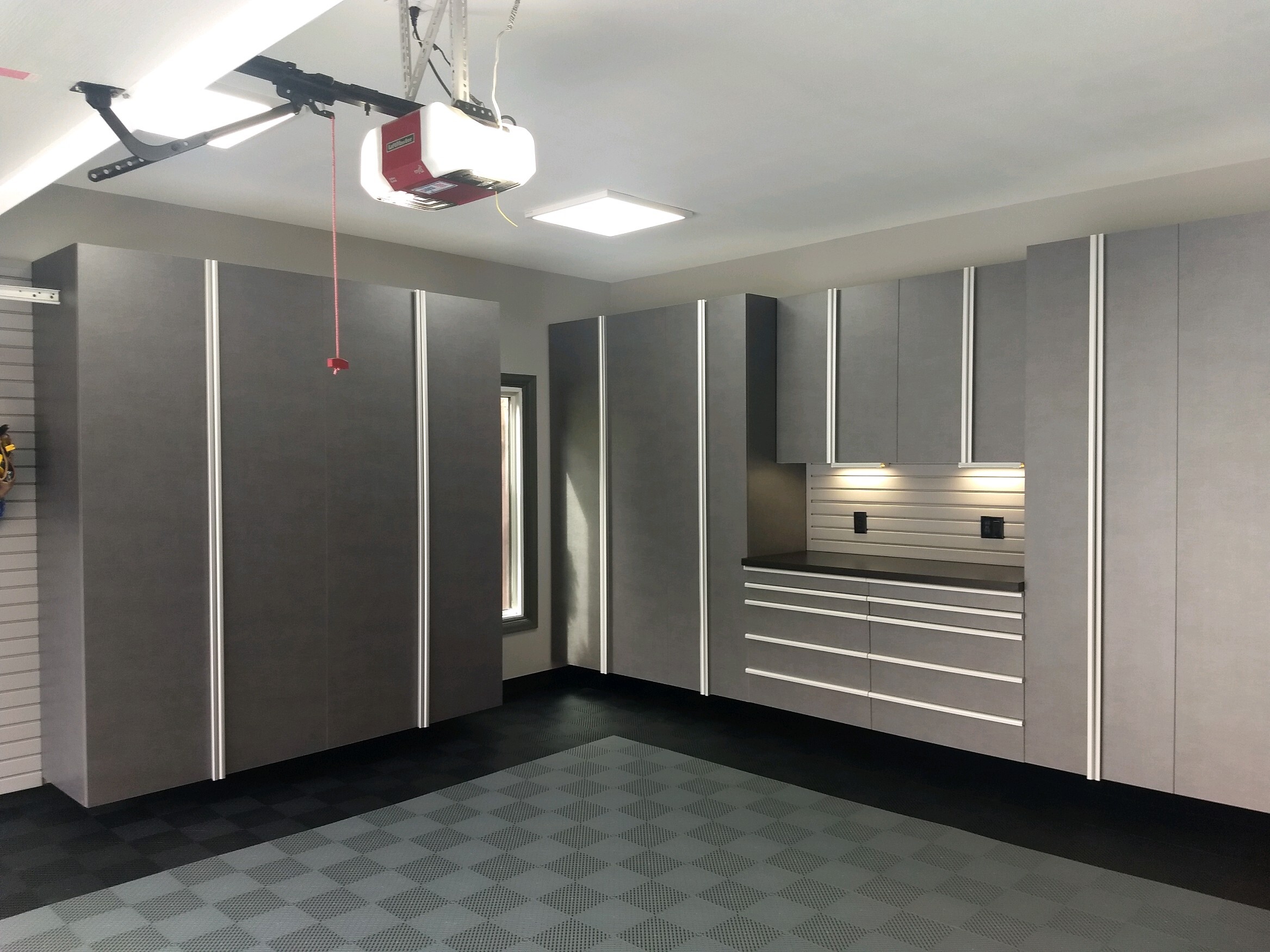 Professionally organized garage with checkered floor, large cabinets and built in workbench. 